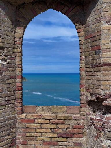Veduta del mare attraverso una finestra di mattoni.
