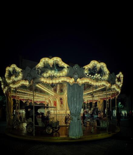 Carosello di giostra illuminato di notte, con luci calde, in un parco giochi all'aperto.