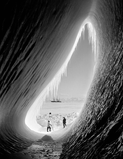 Two explorers looking at their ship, 'Terra Nova', during an Antarctic expedition, 1911